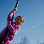 girl on a children’s zip line with a blue sky background