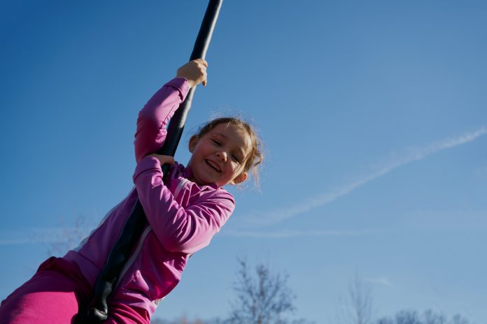 girl on a children's zip line with a blue sky background